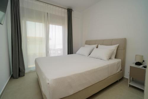 a white bed in a bedroom with a window at Villa Maraboo in Parga