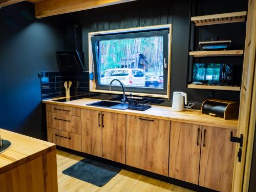 a kitchen with a sink and a large screen television at Lakehouse Lubiatów in Lubiatów