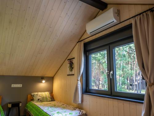 a small bedroom with a bed and a window at Lakehouse Lubiatów in Lubiatów