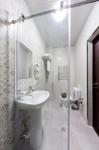 a white bathroom with a sink and a toilet at Centrum Hotel Tashkent in Tashkent