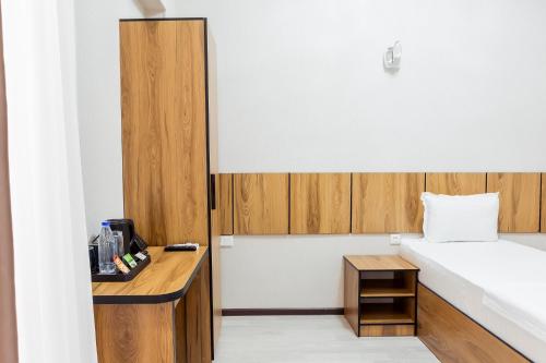 a small room with a bed and a wooden desk at Centrum Hotel Tashkent in Tashkent