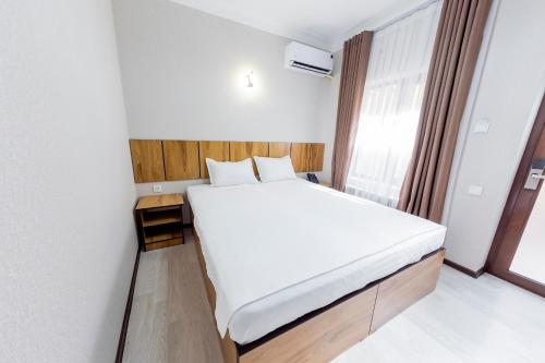 a bedroom with a large white bed and a window at Centrum Hotel Tashkent in Tashkent
