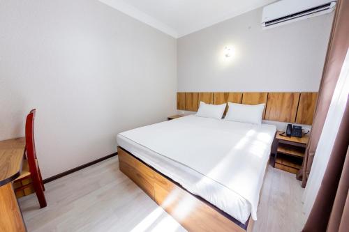 a bedroom with a white bed with a wooden headboard at Centrum Hotel Tashkent in Tashkent
