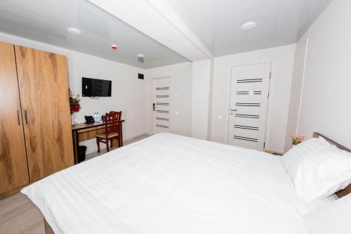 a white bedroom with a bed and a desk at Centrum Hotel Tashkent in Tashkent