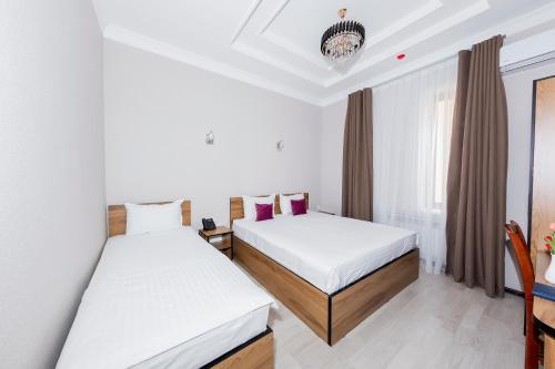a hotel room with two beds and a window at Centrum Hotel Tashkent in Tashkent