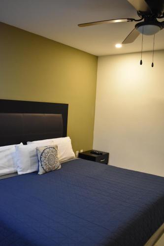 a bedroom with a blue bed with a ceiling fan at Hotel Casa 20 in León
