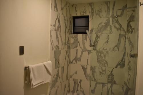 a bathroom with a shower with a marble wall at Hotel Casa 20 in León