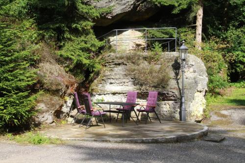 a table and four purple chairs on a patio at Ferienwohnung Jagdschloss Bielatal in Bielatal