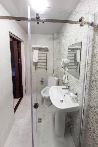 a bathroom with a toilet and a sink and a shower at Centrum Hotel Tashkent in Tashkent