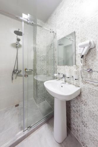a white bathroom with a sink and a shower at Centrum Hotel Tashkent in Tashkent