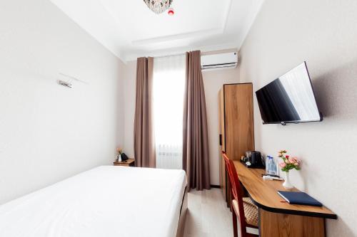 a hotel room with a bed and a desk with a computer at Centrum Hotel Tashkent in Tashkent