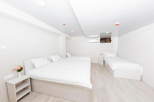 a white bedroom with a bed and a tv at Centrum Hotel Tashkent in Tashkent