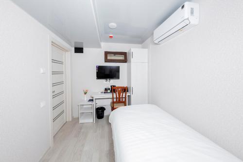 a white bedroom with a bed and a desk at Centrum Hotel Tashkent in Tashkent