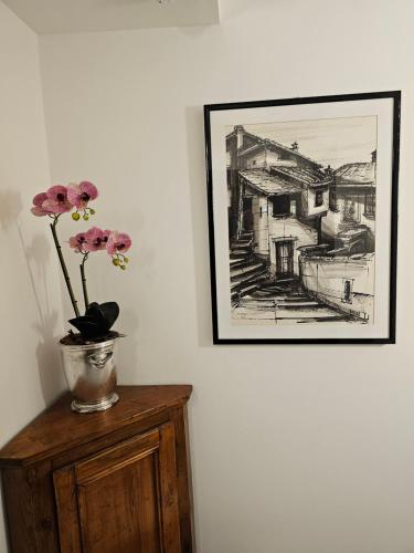 a painting on a wall with flowers in a vase on a cabinet at Victoria Royal Garden in Como