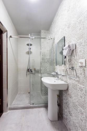 a white bathroom with a shower and a sink at Centrum Hotel Tashkent in Tashkent