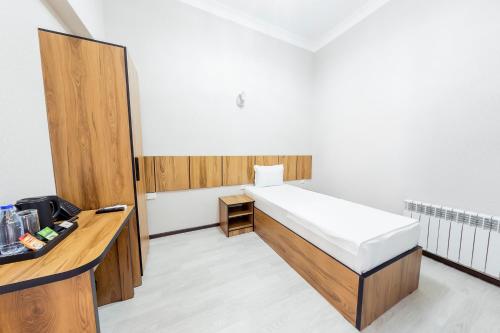 a small room with a bed and a desk at Centrum Hotel Tashkent in Tashkent