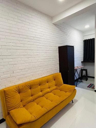 a yellow couch in a room with a brick wall at Unic Residence And Transit Hotel in Katunayake
