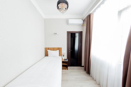 a bedroom with a white bed and a black door at Centrum Hotel Tashkent in Tashkent
