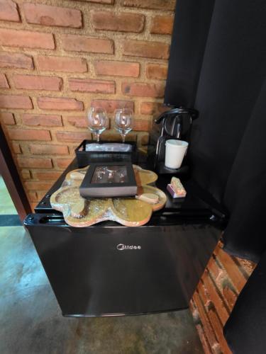 a counter with two glasses and a laptop on it at Cabana Fé Miguel Pereira Chalé Para Casal no Centro MP in Miguel Pereira