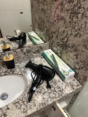 a bathroom counter with a sink and a gun on it at Apartamento Sua Casa em João Pessoa in João Pessoa