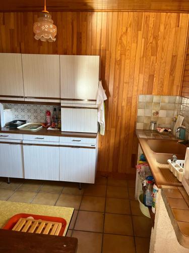 - une cuisine avec des murs en bois, des placards blancs et un évier dans l'établissement Seventies, au Le Verdon-sur-Mer