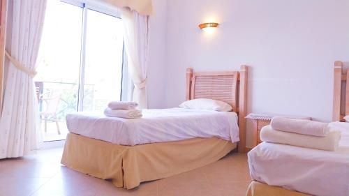 une chambre avec deux lits et une grande fenêtre dans l'établissement Algarver I - Boavista Golf Fairview SwimPool Villa, à Lagos