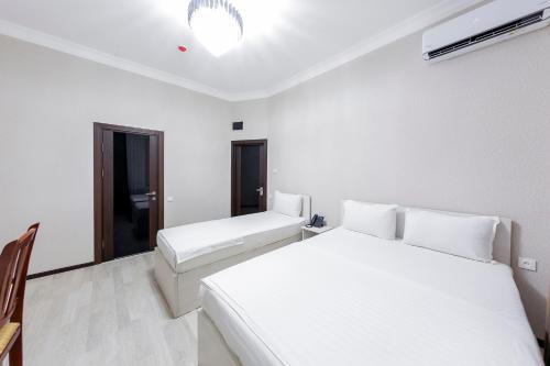 a white room with two beds and a window at Centrum Hotel Tashkent in Tashkent