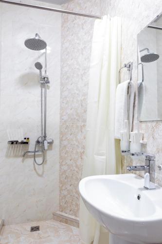 a white bathroom with a sink and a shower at Centrum Hotel Tashkent in Tashkent