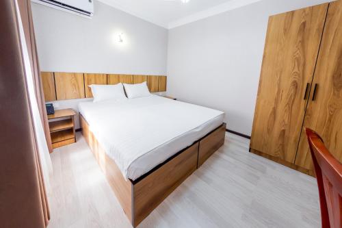 a small bedroom with a bed and wooden cabinets at Centrum Hotel Tashkent in Tashkent