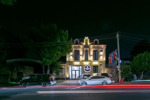 two cars parked in front of a building at night at Centrum Hotel Tashkent in Tashkent