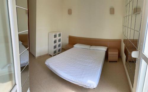 ein kleines Schlafzimmer mit einem weißen Bett und einem Spiegel in der Unterkunft Modern Penthouse-duplex Facing The Sea in La Torre