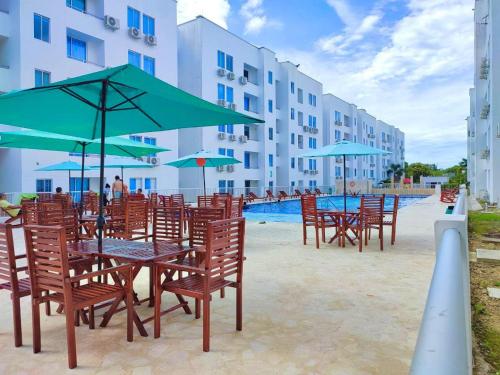 a group of tables and chairs with umbrellas next to a pool at Vacaciones Inolvidables in Coveñas