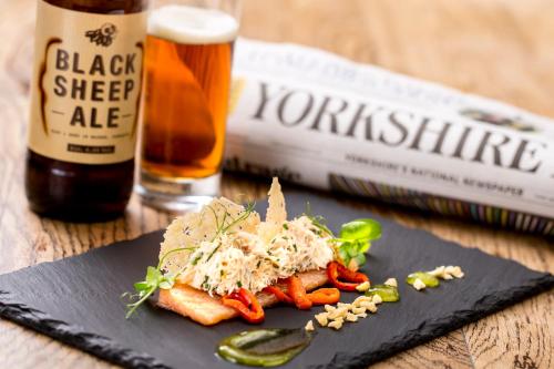 a plate of food on a table with a bottle of beer at Hazlewood Castle & Spa in Tadcaster