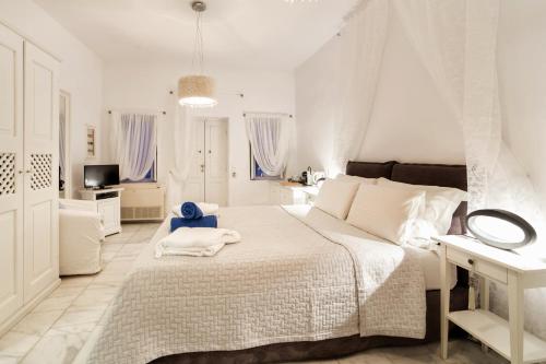 a white bedroom with a bed and a television at Armeni Village in Oia