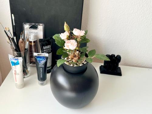 a black vase with pink flowers on a counter at Bears View BB in Bern