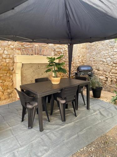 a black table and chairs under an umbrella at Maison cosy avec cour privée - Calme et nature, La Trimouille in La Trimouille