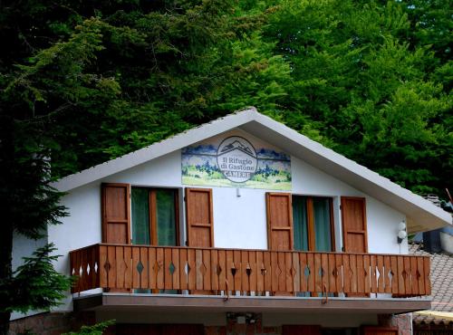 a small house with a wooden balcony and trees at IL RIFUGIO DI GASTONE - Monte Amiata - Macinaie - in Castel del Piano