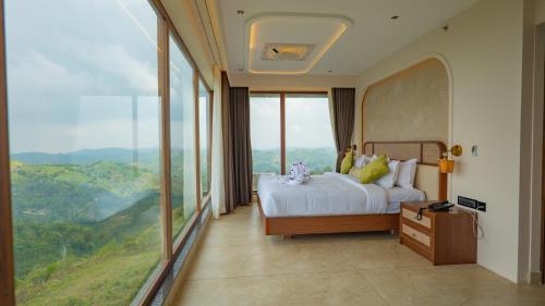 a bedroom with a bed and a large window at Palette Hill View Resorts Vagamon in Vagamon