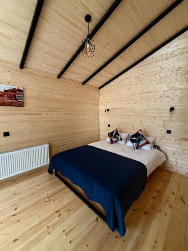 a bedroom with a bed in a wooden wall at Kazbegi Inn Cottages in Stepantsminda