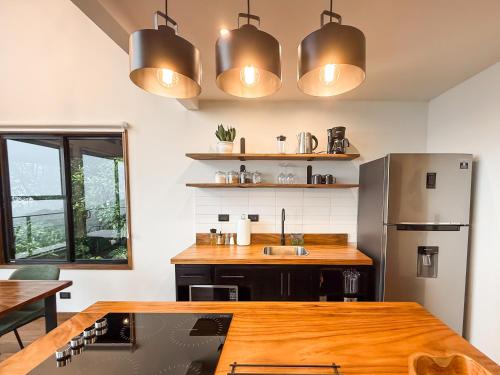 a kitchen with a wooden table and a refrigerator at Ananta Forest - Sunset & Gulf View - Glamping Dome and Mountain House in Monteverde Costa Rica