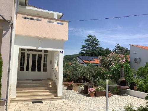 a white house with stairs and flowers in a yard at Apartment Vitezic in Punat