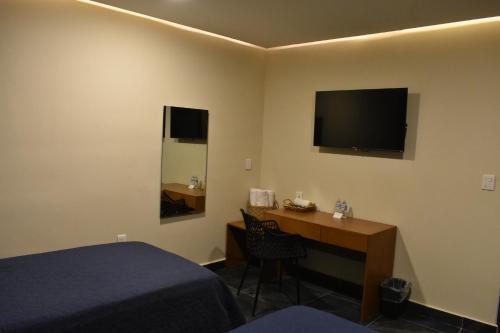 a hotel room with a desk and a television on the wall at Hotel Casa 20 in León