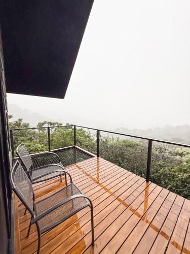 a balcony with two chairs on a wooden deck at Ananta Forest - Sunset & Gulf View - Glamping Dome and Mountain House in Monteverde Costa Rica