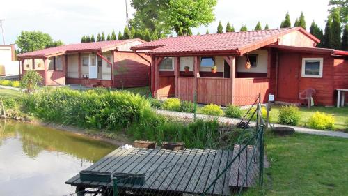 a red house with a deck next to a river at Pokoje Żabi Staw in Mikołajki