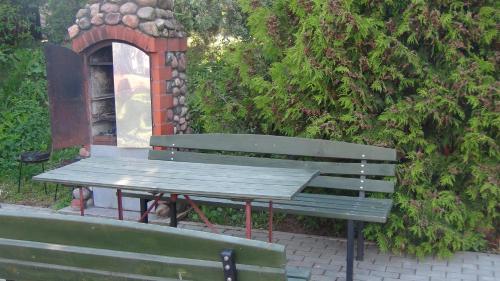a park bench with a picnic table next to a bush at Pokoje Żabi Staw in Mikołajki