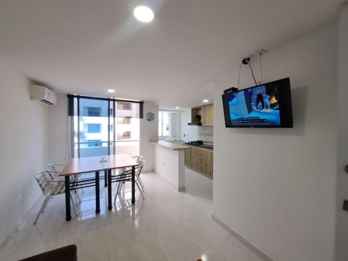 a living room with a table and a tv on a wall at Vacaciones Inolvidables in Coveñas