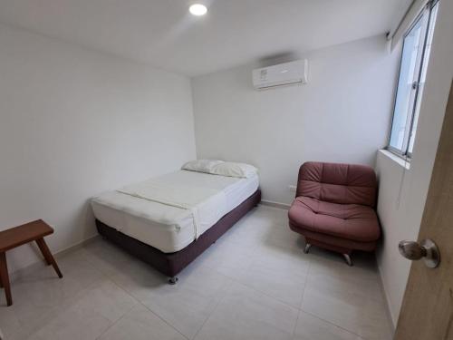 a small bedroom with a bed and a chair at Vacaciones Inolvidables in Coveñas
