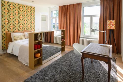 a bedroom with a bed and a desk and a table at De Visitatie Rupelmonde in Rupelmonde