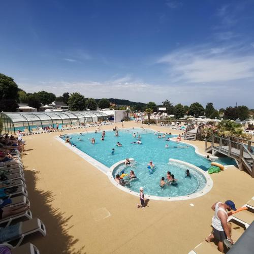 un groupe de personnes dans une piscine d'un complexe hôtelier dans l'établissement Houlgate-420- Mobilhome cosy 3 chambres 6 personnes Camping 5 étoiles, à Houlgate