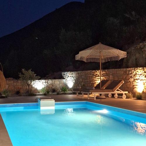 a swimming pool with an umbrella and a table and bench at Azzurro Mare in Póndi
